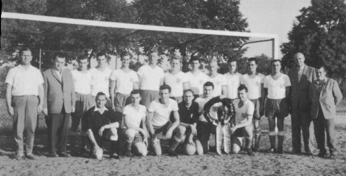 Fußballmannschaft mit Betreuern und Pokal auf dem Sportplatz